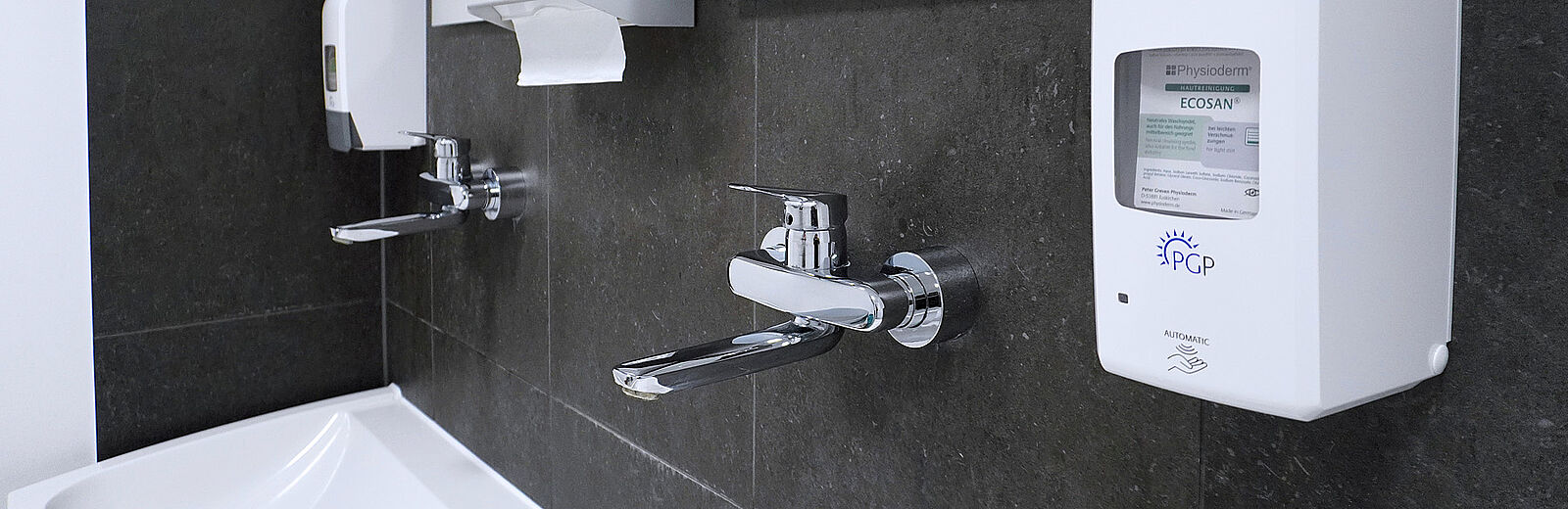 Waschbecken mit zwei Armaturen und automatischen Seifenspendern – hygienische, barrierearme Ausstattung.