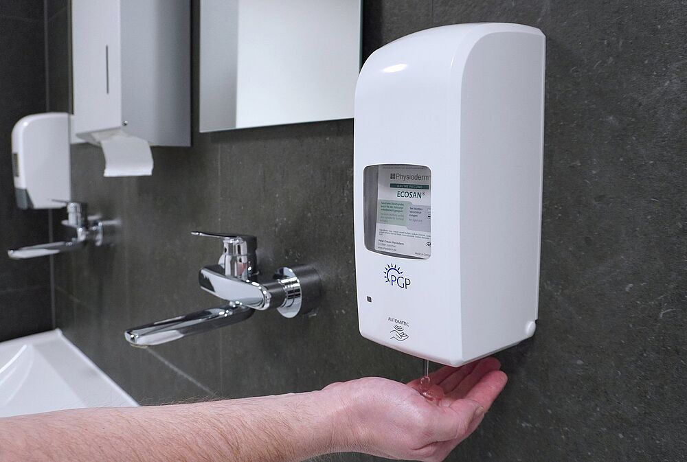 Person hält die Hand unter einen automatischen Seifenspender – berührungslose, hygienische Bedienung.