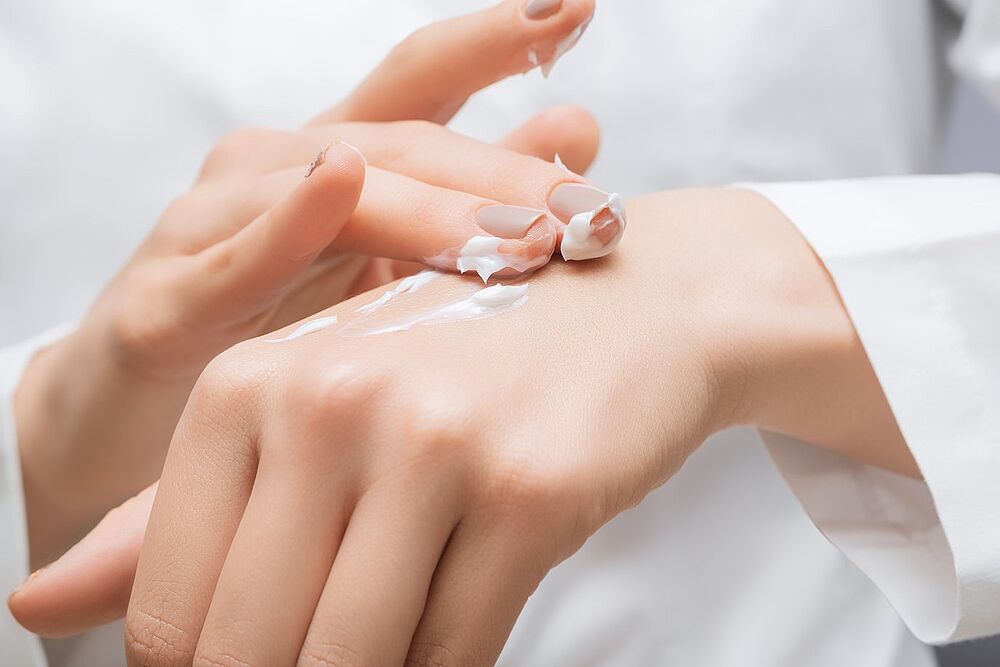 Person trägt Handcreme auf – Symbol für Pflege und Schutz der Haut.